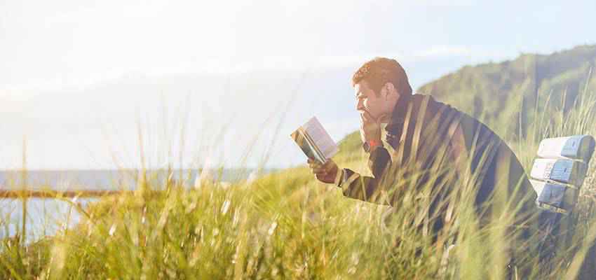 Un hombre leyendo al aire libre.