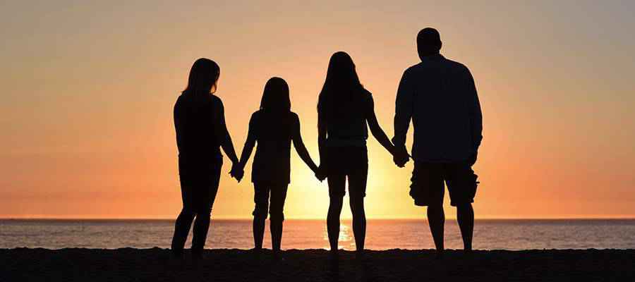 Una familia tomados de la mano en la playa.