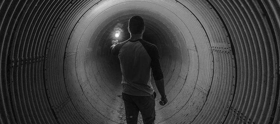 Une personne tenant une lumière dans un tunnel sombre.