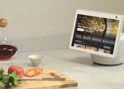 En la imagen, Echo Show se para en una mesa de cocina junto a una tabla de cortar con algo de comida.