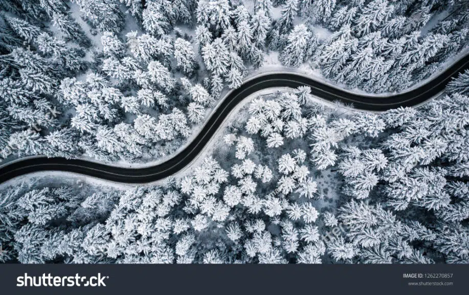 Kurvige Straße mit Schnee und Bäumen