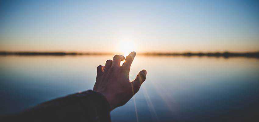 Una mano protesa verso il sole.